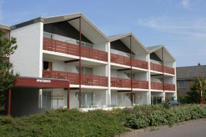 een appartementencomplex met rode balkons bij Motel Texel in De Koog
