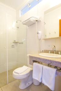 a white bathroom with a toilet and a sink at Pousada Il Villaggio in Santo Antônio do Pinhal