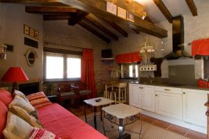 uma sala de estar com um sofá vermelho e uma cozinha em Casa Concejos em San Román de Cameros