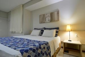 a bedroom with a blue and white bed and a lamp at Littoral Express in João Pessoa