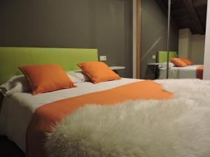 1 dormitorio con 2 camas y almohadas de color naranja y blanco en Casa Bielsa, en Mosqueruela