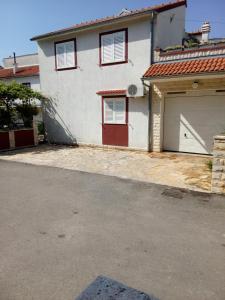 a white house with red doors and a garage at Petra in Vodice