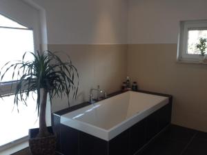a bathroom with a large white tub and a potted plant at Ferienhaus Frankstraße 5b in Zinnowitz +14 photos