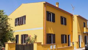 a yellow house with black shutters on it at CASA VACANZA VALLEDORIA 2 in Valledoria