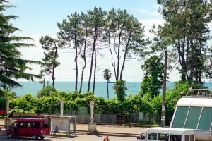 a red van parked on a street next to trees at Apartments Georgia in Makhinjauri