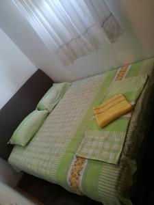 un letto con trapunta e cuscini verdi e una finestra di Apartment Sara a Podgorica