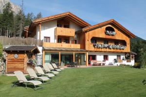 a group of chairs on a lawn in front of a house at Garni Ciasa Urban in Badia