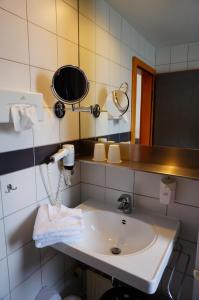 
a white sink sitting under a mirror in a bathroom at Ringhotel Altstadt in Güstrow
