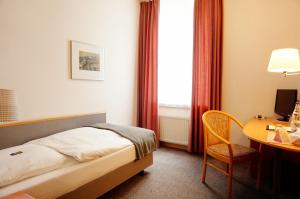 a hotel room with a bed and a desk with a computer at Ringhotel Altstadt in Güstrow