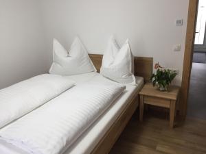 een bed met witte lakens en kussens erop bij Ferienwohnung Imbach in Kaprun