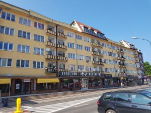 duży żółty budynek z balkonami na ulicy w obiekcie Apartament Mieszko Kołobrzeg w Kołobrzegu