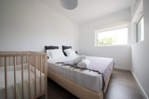 a white bedroom with a crib with a teddy bear on it at Quinta do Meco - Beach & Nature in Aldeia do Meco +37 photos