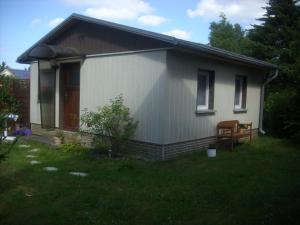 une petite maison blanche avec un banc dans une cour dans l'établissement Haus Stefanie, à Heringsdorf