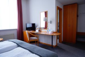 a bedroom with a desk with a computer and a bed at Ringhotel Altstadt in Güstrow