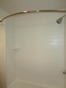a shower in a bathroom with a white wall at Old Town Inn in San Diego