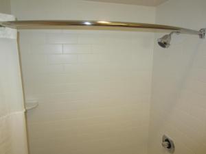 a bathroom with a shower with a white tiled wall at Old Town Inn in San Diego