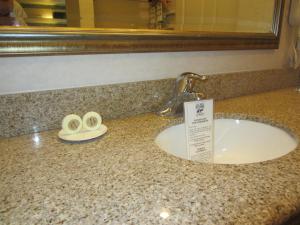 a bathroom counter with a sink and a mirror and towels at Old Town Inn in San Diego