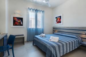 a bedroom with a bed with a blue blanket and a desk at Reef and Dream in San Vito lo Capo