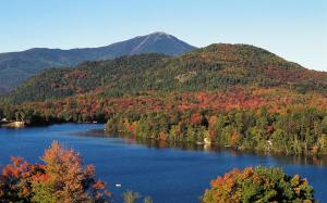 a lake in the middle of a forest with a mountain at Crowne Plaza Lake Placid, an IHG Hotel in Lake Placid