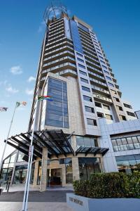 ein hohes Gebäude mit einer Flagge davor in der Unterkunft The Spencer Hotel in Auckland