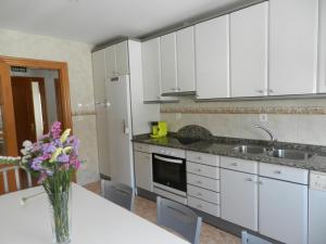 una cocina con armarios blancos y un jarrón de flores sobre una mesa en Lagunen Etxea, en Muniáin de la Solana