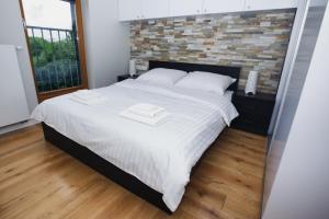 a bedroom with a large white bed with a brick wall at Apartament "Park Lotników" in Kraków