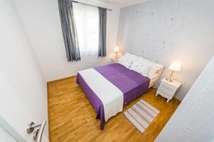 a bedroom with a purple bed and a window at Apartmani Paradise in Petrcane