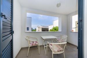 a table and chairs on a balcony with a window at Apartmani Paradise in Petrcane