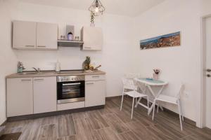 une cuisine avec des placards blancs et une table avec des chaises dans l'établissement Apartment Barka, à Split