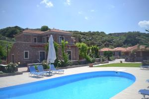 a villa with a swimming pool in front of a house at Molivos Castle Apartments in Mythimna