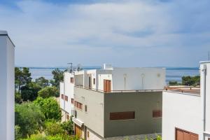 a white building with the ocean in the background at Apartmani Paradise in Petrcane