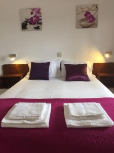 a large white bed with two white towels on it at Slow house d'encosta in São Brás de Alportel