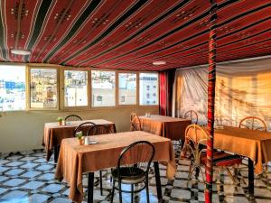 a restaurant with tables and chairs in a room with windows at Orient Gate in Wadi Musa