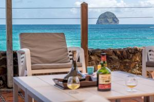 a table with two bottles of wine and a view of the ocean at La Sirene du Diamant, villa de luxe sur la plage,18 personnes in Le Diamant
