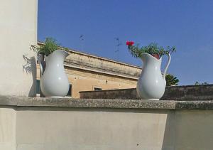 zwei weiße Vasen auf einem Felsvorsprung mit Blumen in der Unterkunft B&B Corte dell' Idume in Lecce