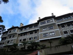 un gran edificio con palmeras delante en Duplex Accorsi Gramado, COM 2 SUITES, en Gramado