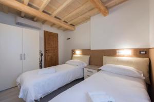 two beds in a room with white walls and wooden ceilings at Il Limone in Florence