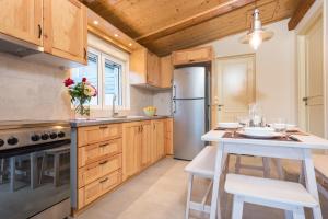 a kitchen with wooden cabinets and a stainless steel refrigerator at Amygdalia Villa with Private Pool, by ZanteWize in Pandokrátor