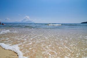 a beach with the ocean and people in the water at House Katerina Mediterranean in Sarti