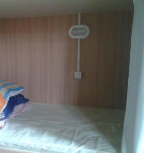 a bed in a room with a wooden wall at Hostel Quintal do Rosa in Praia do Rosa