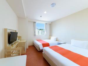 a hotel room with two beds and a television at Hotel Abest Naha Kokusaidori in Naha