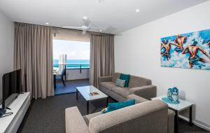 a living room with a couch and a tv at Synergy Broadbeach - Official in Gold Coast
