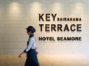 Shirahama Key Terrace Hotel Seamore في شيراهاما: شاب صغير يمشي أمام لافتة الفندق