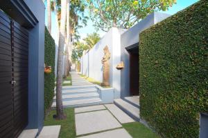 a walkway with a statue next to a white wall at Kembali Villas in Seminyak