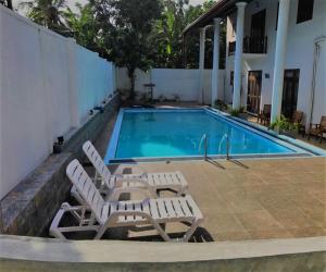 a swimming pool with two lounge chairs next to a house at Villa 234 in Galle
