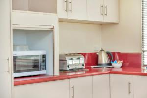 a kitchen with white cabinets and a microwave at All Decked Out - Port Willunga - C21 SouthCoast Holidays in Port Willunga