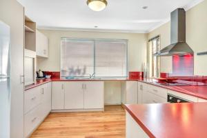 a kitchen with white cabinets and red counter tops at All Decked Out - Port Willunga - C21 SouthCoast Holidays in Port Willunga