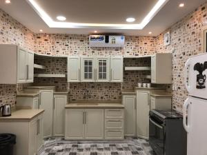 een keuken met witte kasten en een witte koelkast bij Kendah Chalet in Buraydah