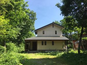 a small white house in the middle of a field at Shirokuma Lodge Hakuba in Hakuba