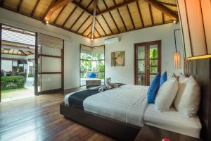 a bedroom with a large bed with blue and white pillows at Arama Riverside 5 Bedrooms by Villas Direct Bali in Legian +84 photos